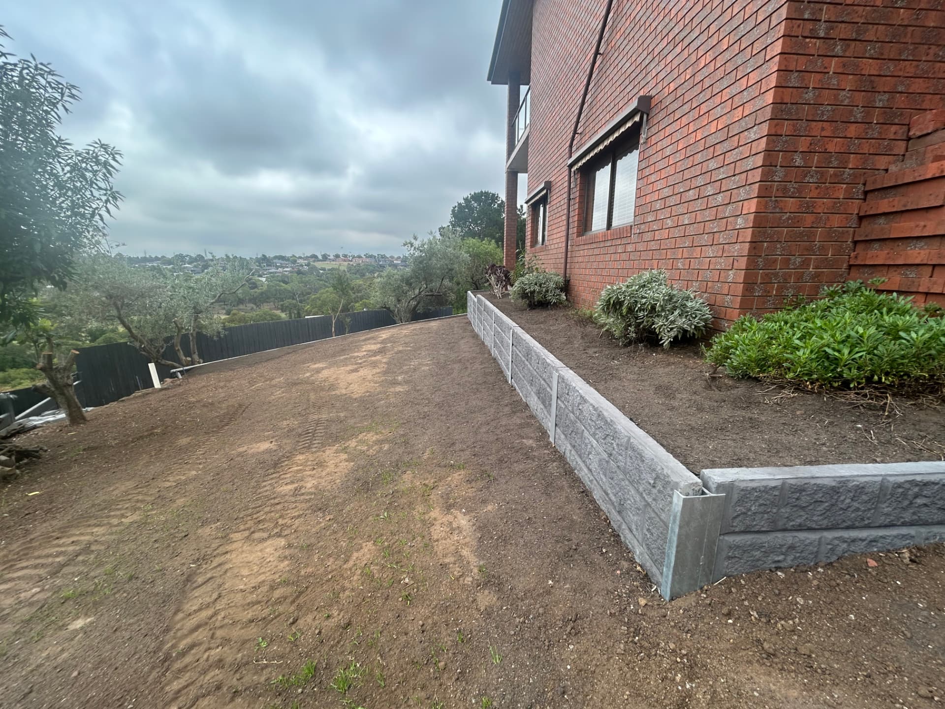 Concrete sleeper wall running along the side of the house with the ground levelled