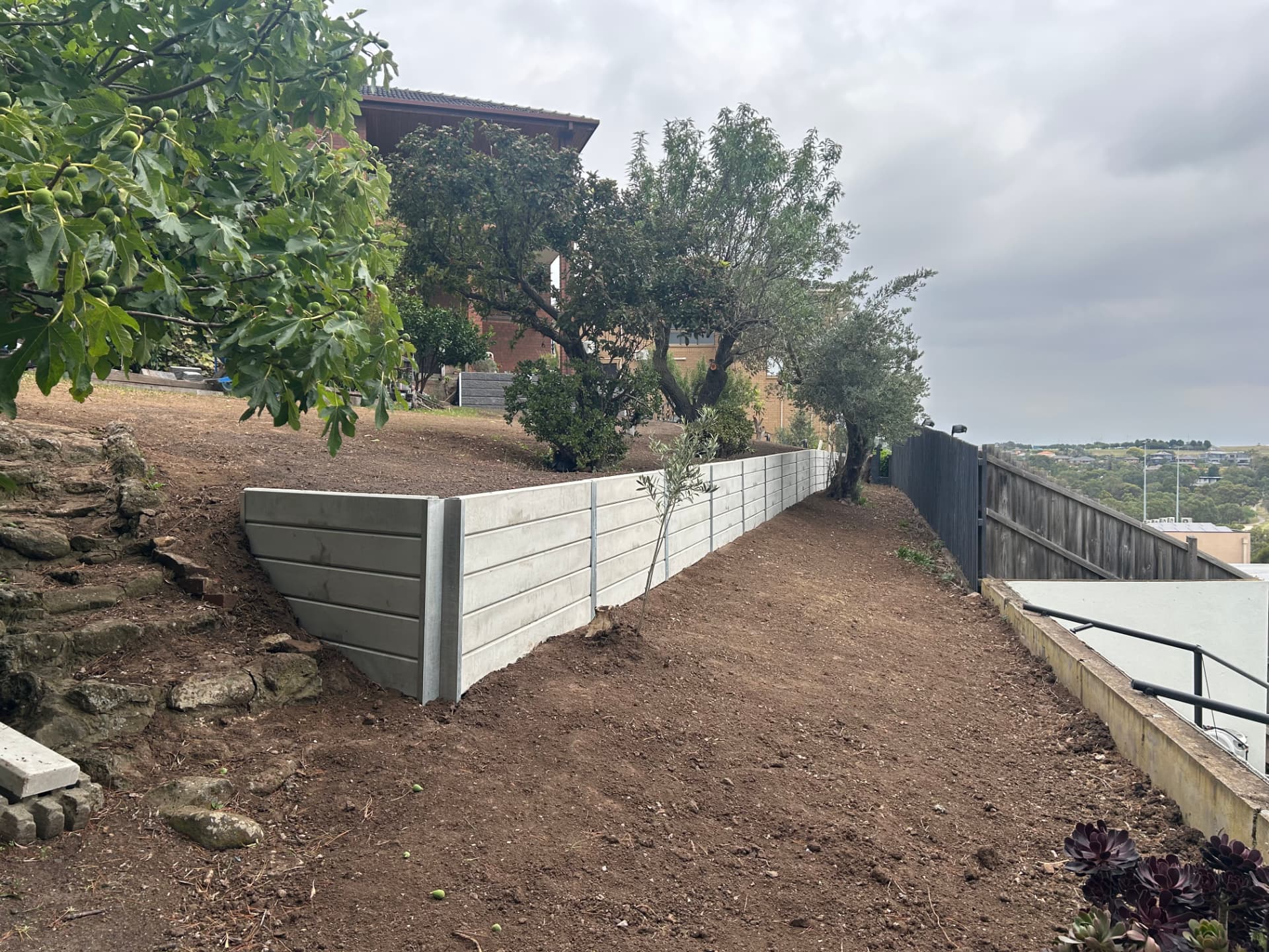 New concrete sleeper wall along the upper path with clean graded ground