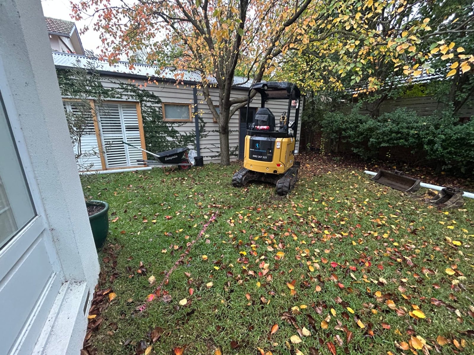 Branded Rigid Earthworks excavator parked on an intact lawn before trenching begins