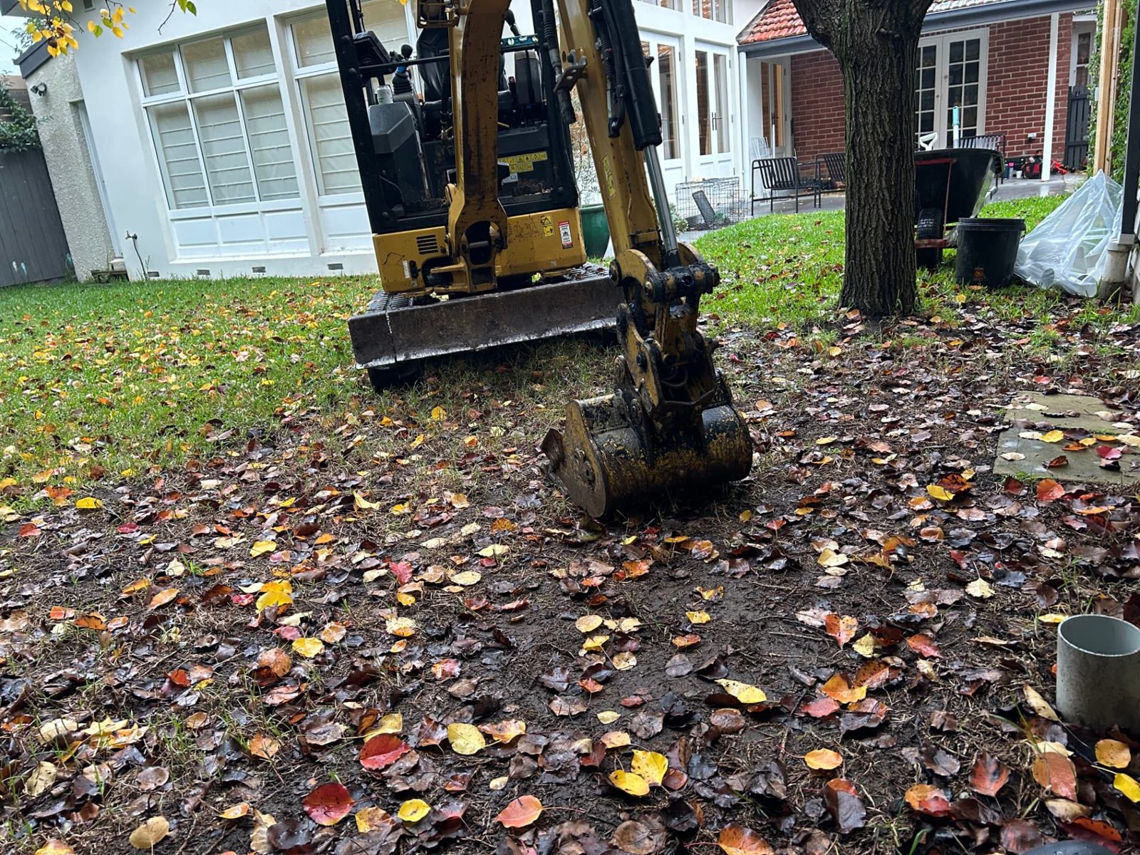 Excavator bucket breaking the surface of the lawn to open the trench line