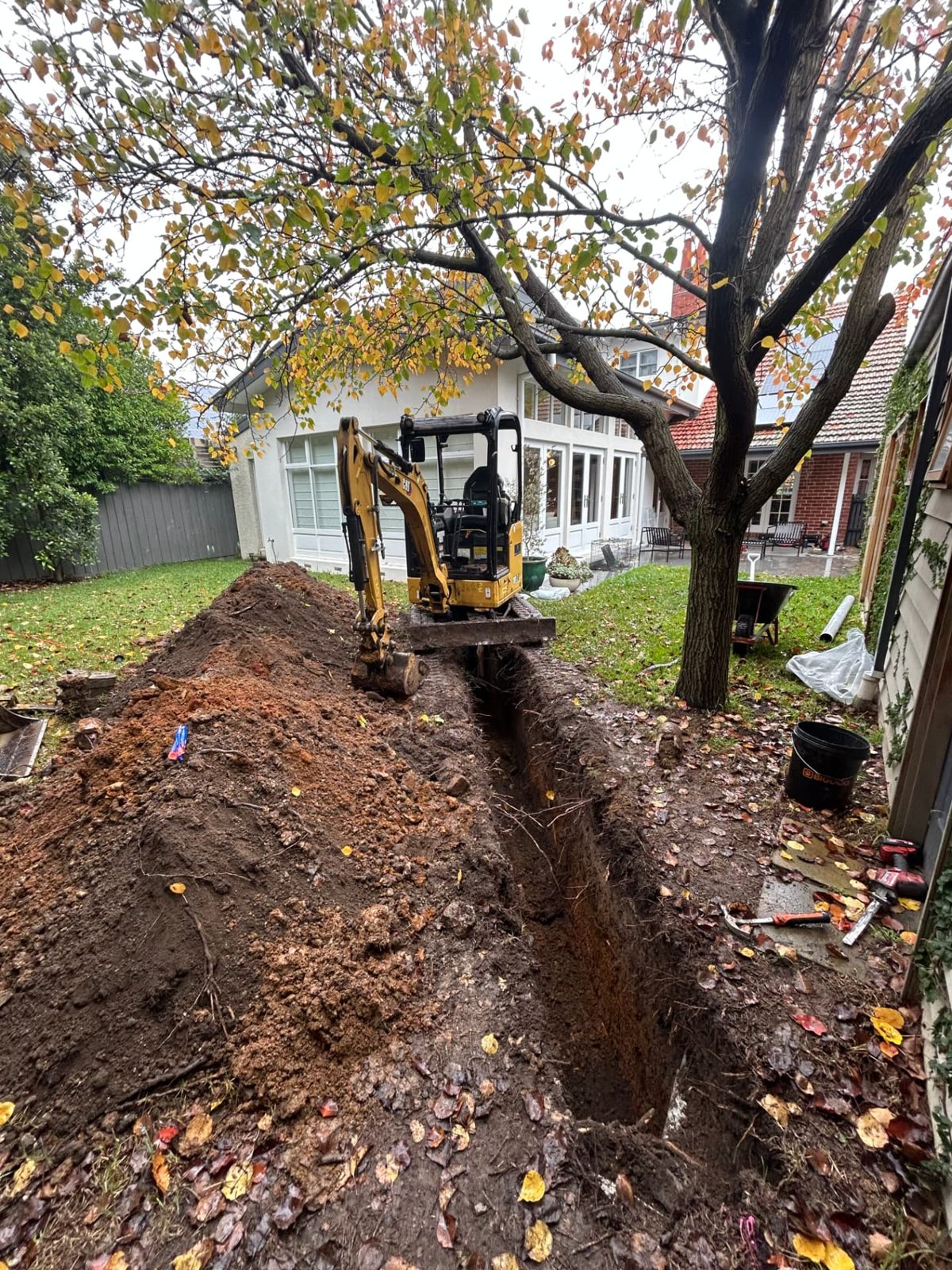Trench line carried across the lawn towards the house with spoil windrowed along one side