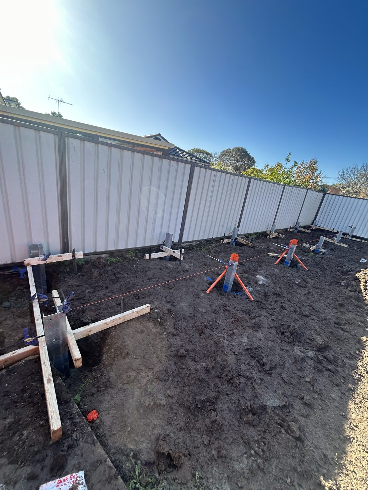 String lines and braced galvanised retaining wall posts set out along a boundary fence