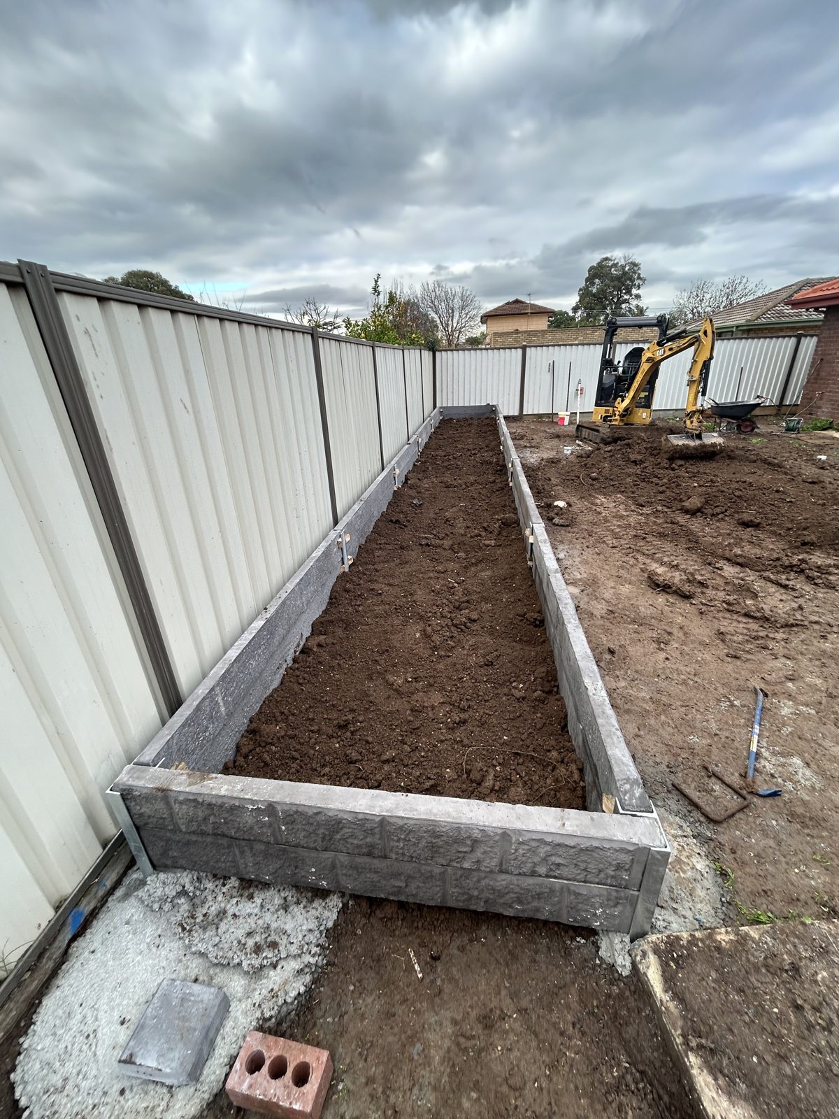 Concrete sleeper garden bed wall running the length of the boundary fence