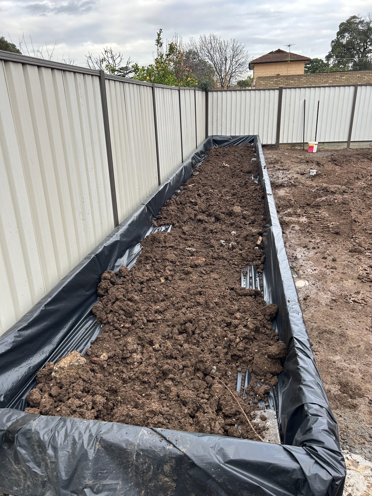 Waterproof membrane behind the sleeper wall with soil backfilled into the bed